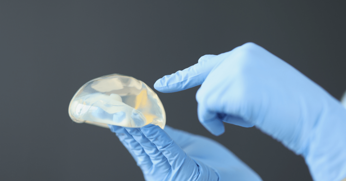 doctor with blues gloves holding breast implant